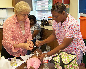 Codwell ES Nurse Carla Carter (right) learns the correct way to perform a gastrostomy feeding from HISD Nurses Joan Maset (left) and Linda Hill (seated).